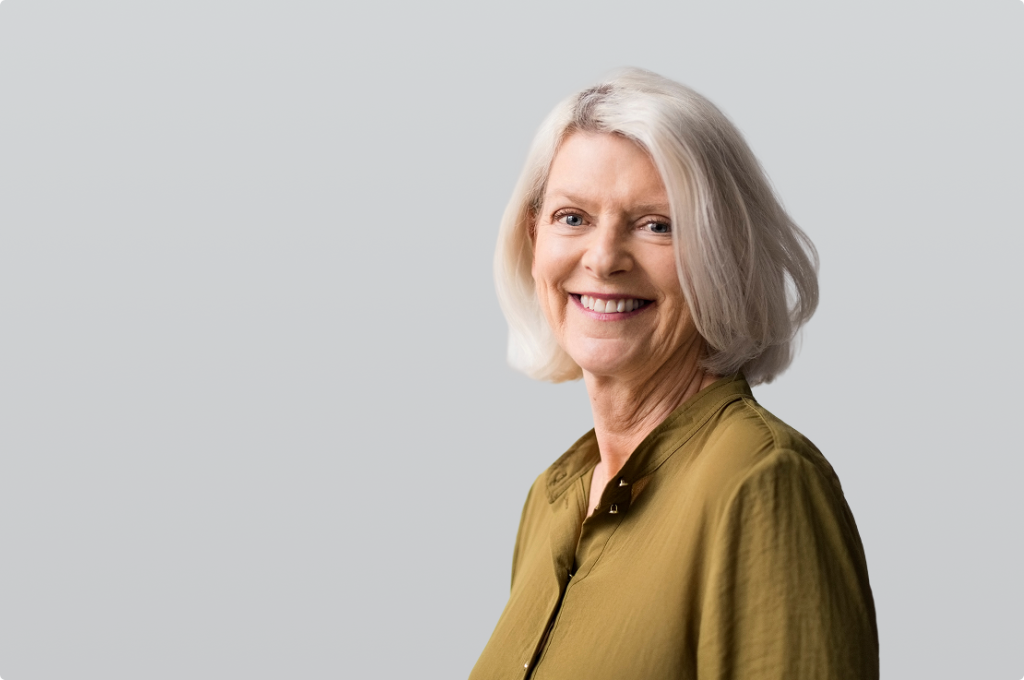 Shows an older woman smiling into the camera