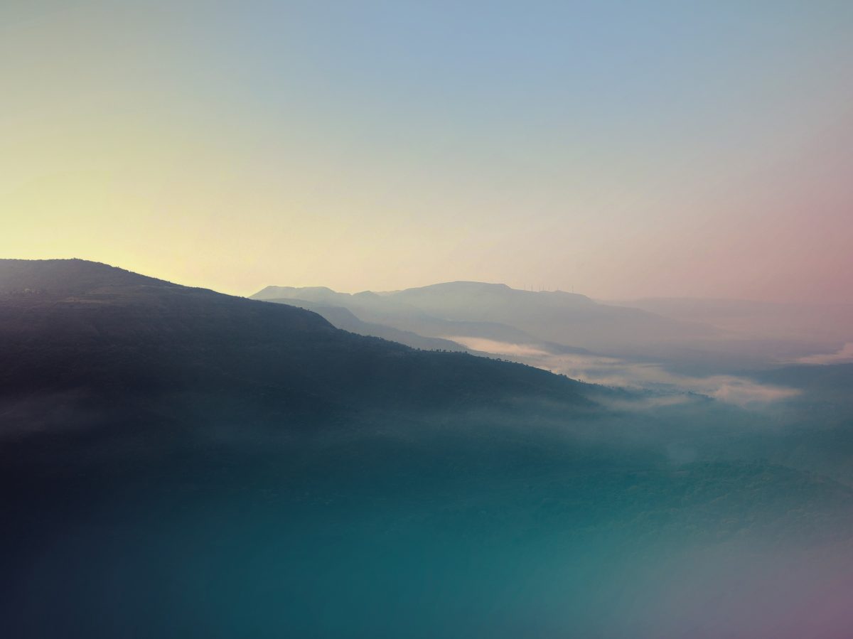 The sun rising behind mountains and a clear sky