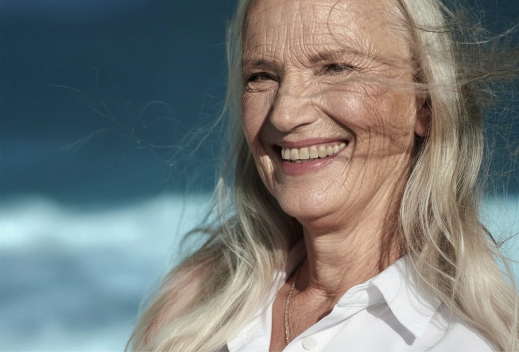 An older woman smiling and enjoying a day at the beach